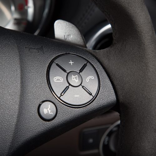 A closeup of control buttons on the steering wheel of a luxury car under the lights
